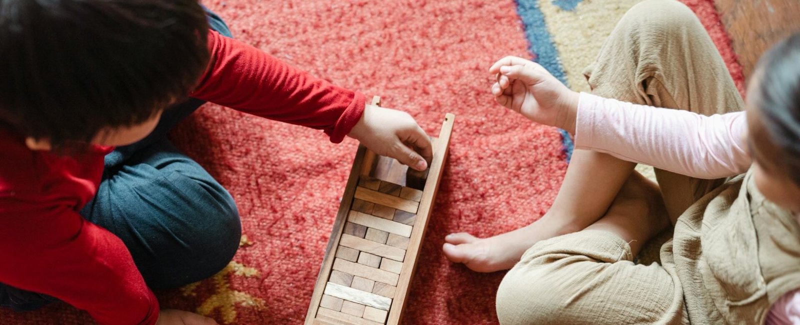 crop cute kids playing jenga on floor at home