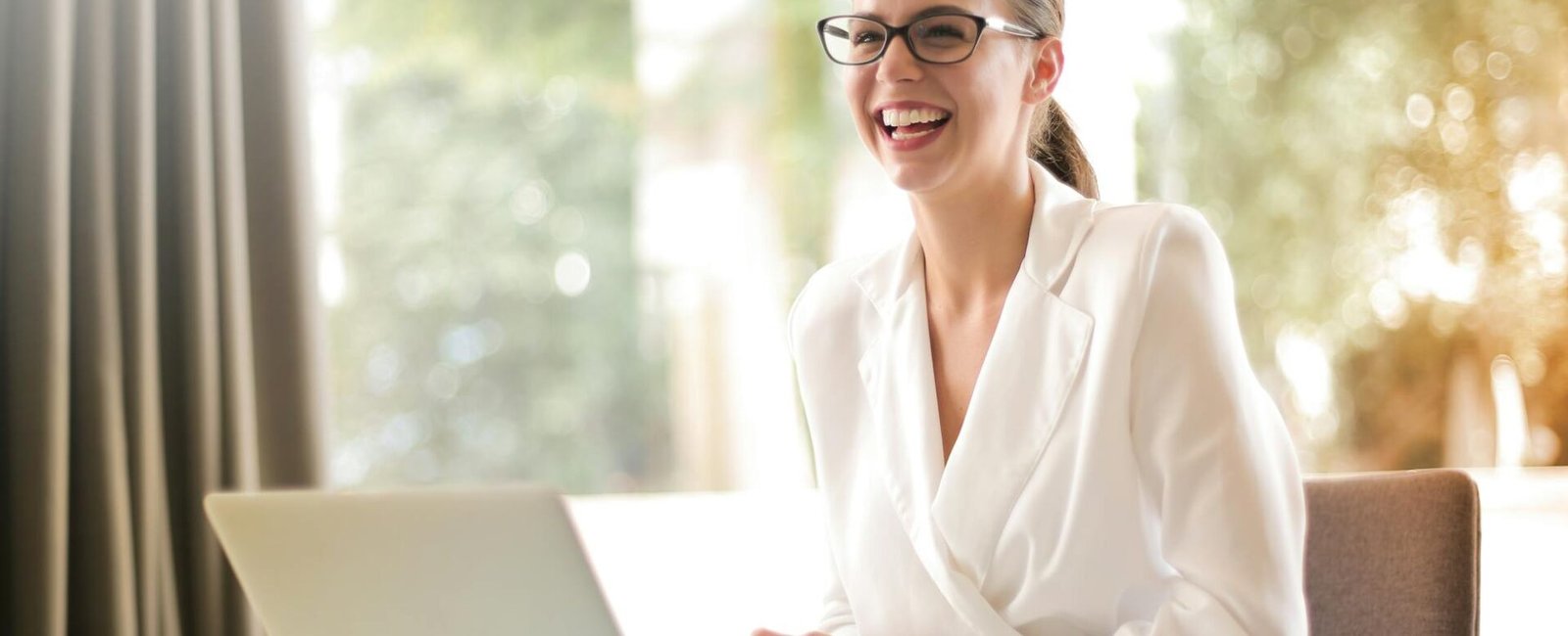 laughing businesswoman working in office with laptop