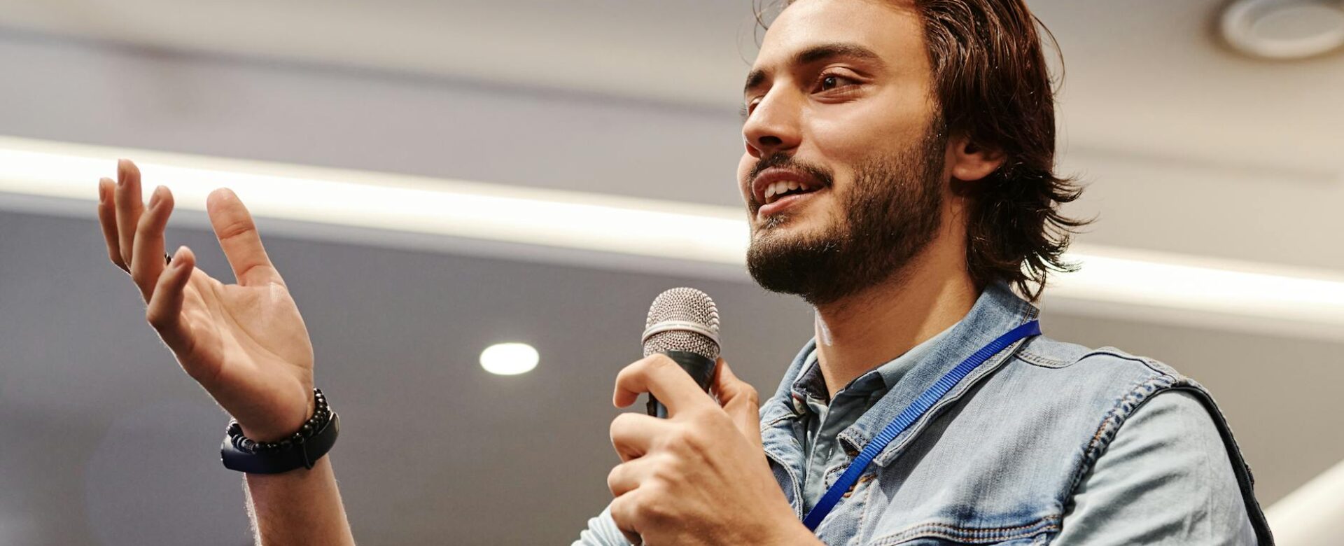 man in blue denim vest holding microphone