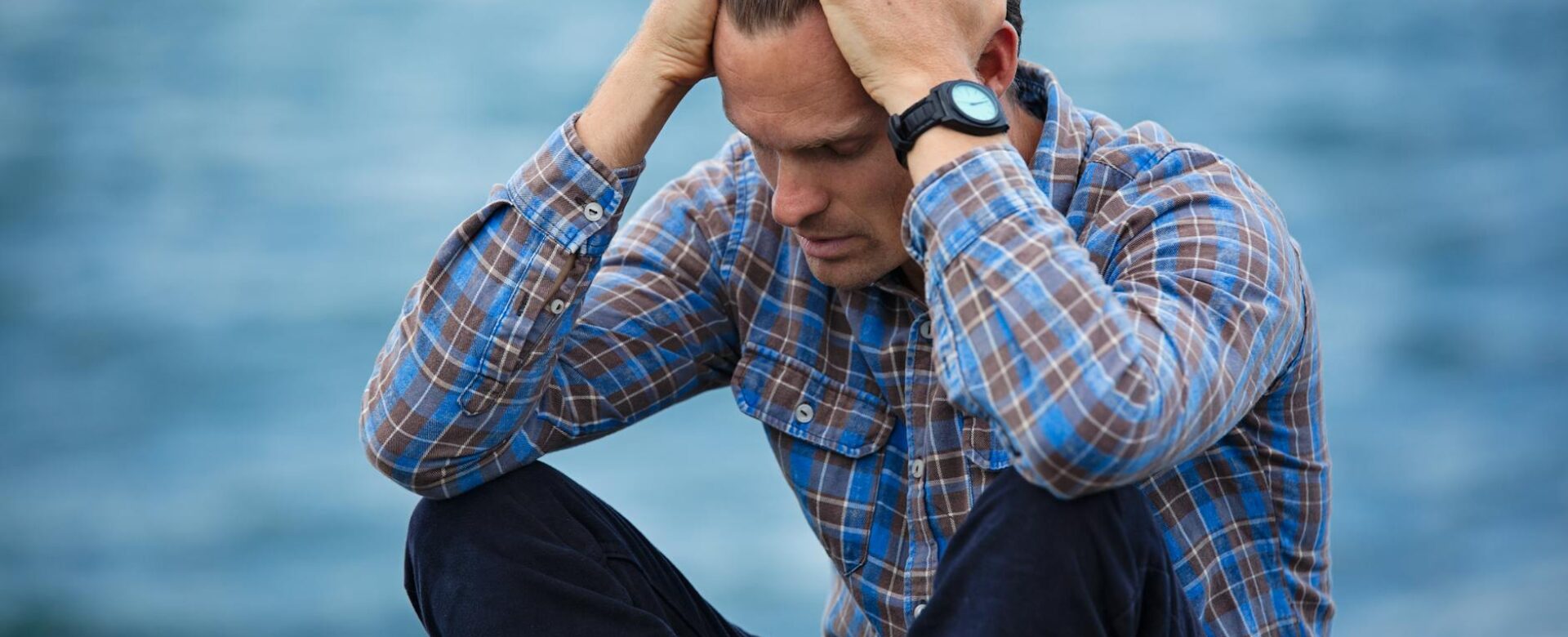 man in blue and brown plaid dress shirt touching his hair