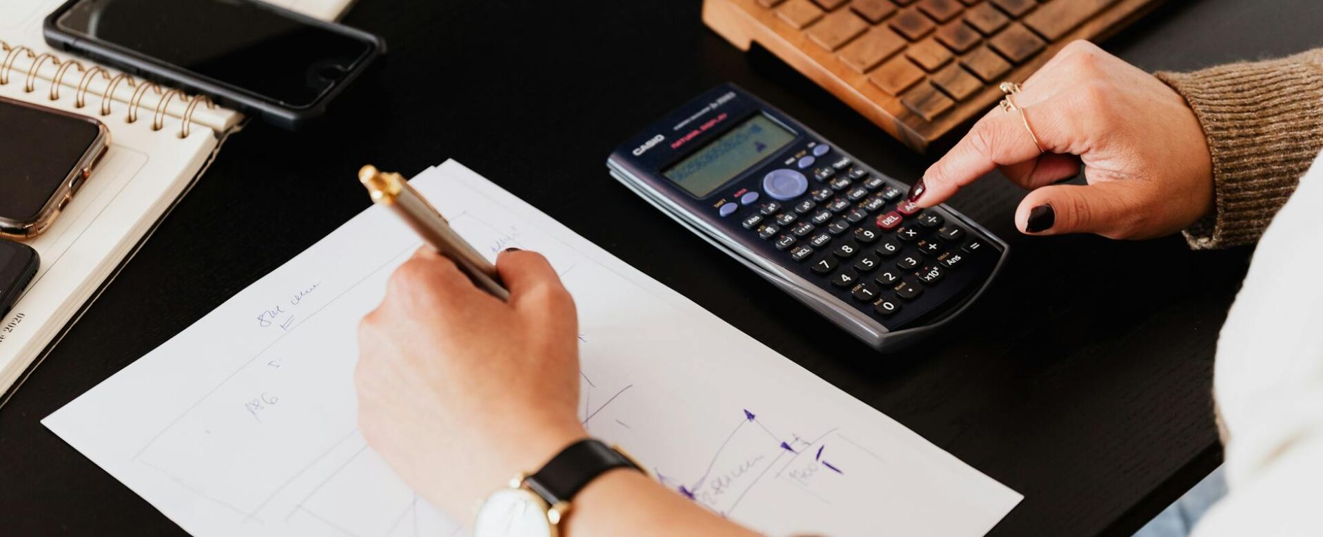 bookkeeper writing down on paper while using calculator