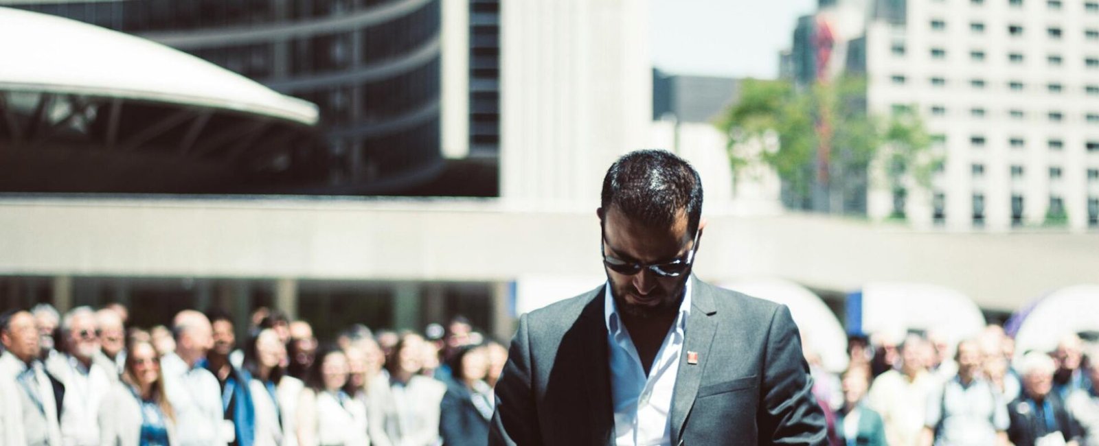 selective focus photography of man holding smartphone while standing near people
